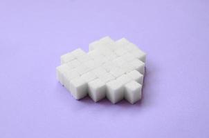 A heart made of sugar cubes lies on a trendy pastel violet background photo