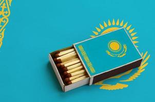 Kazakhstan flag is shown in an open matchbox, which is filled with matches and lies on a large flag photo