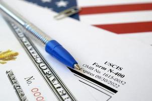 N-400 Application for Naturalization and Certificate of naturalization lies on United States flag with blue pen from Department of Homeland Security photo