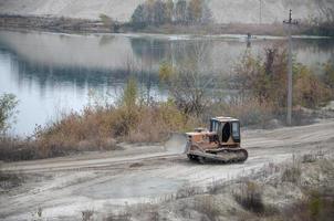 agregado de cantera con maquinaria pesada. Excavadora de oruga con retroexcavadora que conduce a la cantera del sitio de construcción foto