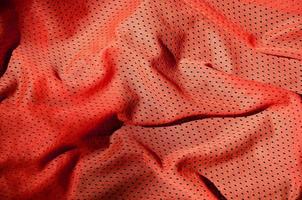 Sport clothing fabric texture background. Top view of red polyester nylon cloth textile surface. Colored basketball shirt with free space for text photo