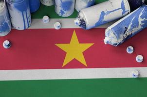 Suriname flag and few used aerosol spray cans for graffiti painting. Street art culture concept photo