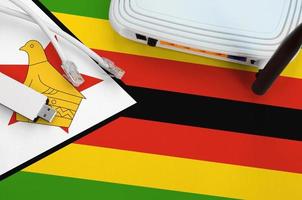 Zimbabwe flag depicted on table with internet rj45 cable, wireless usb wifi adapter and router. Internet connection concept photo