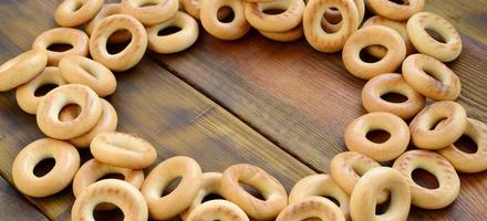 A lot of fresh yellow bagels lie on the surface of the old dark wood. A popular kind of flour products. One of the traditional Russian treats for tea photo