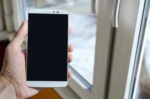 A man is holding a smartphone with an empty black screen in his hand. Copy space for text photo