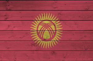 Kyrgyzstan flag depicted in bright paint colors on old wooden wall. Textured banner on rough background photo