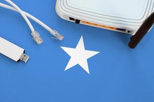 Somalia flag depicted on table with internet rj45 cable, wireless usb wifi adapter and router. Internet connection concept photo