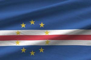 Cabo verde flag with big folds waving close up under the studio light indoors. The official symbols and colors in banner photo