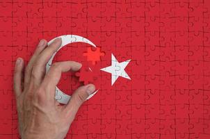 Turkey flag is depicted on a puzzle, which the man's hand completes to fold photo