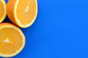 Top view of a several orange fruit slices on bright background in blue color. A saturated citrus texture image photo