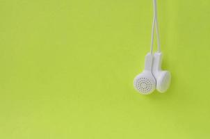 auriculares modernos blancos colgados en un fondo de lima brillante foto