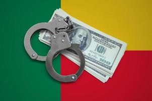Benin flag with handcuffs and a bundle of dollars. Currency corruption in the country. Financial crimes photo