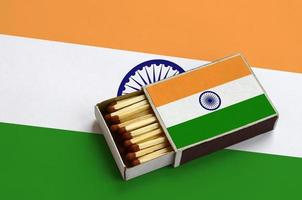 India flag is shown in an open matchbox, which is filled with matches and lies on a large flag photo