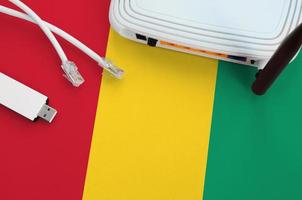 Guinea flag depicted on table with internet rj45 cable, wireless usb wifi adapter and router. Internet connection concept photo