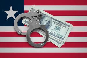 Liberia flag with handcuffs and a bundle of dollars. Currency corruption in the country. Financial crimes photo