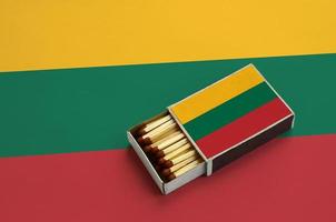 Lithuania flag is shown in an open matchbox, which is filled with matches and lies on a large flag photo