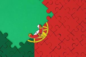 Portugal flag is depicted on a completed jigsaw puzzle with free green copy space on the left side photo