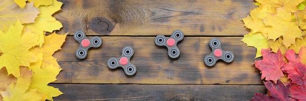 Several spinners among the many yellowing fallen autumn leaves on the background surface of natural wooden boards of dark brown color photo