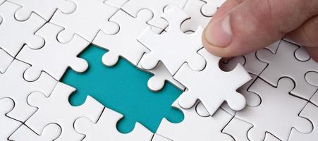 The human hand fills the last missing elements of the surface from the jigsaw puzzle. The concept of the completion of the initiated cases photo