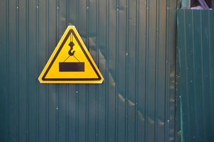 Traffic sign with a picture of a large and heavy square slab hanging from a lifting crane cable. Construction work is underway photo