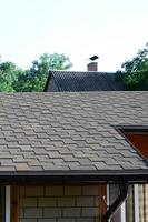 Modern roofing and decoration of chimneys. Flexible bitumen or slate shingles photo