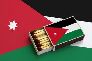 la bandera jordana se muestra en una caja de fósforos abierta, que está llena de fósforos y se encuentra sobre una bandera grande foto