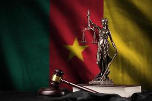 Cameroon flag with statue of lady justice, constitution and judge hammer on black drapery. Concept of judgement and guilt photo