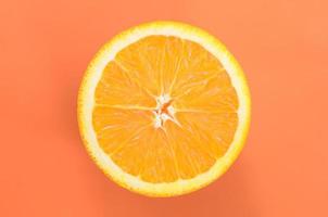 Top view of a one orange fruit slice on bright background in orange color. A saturated citrus texture image photo