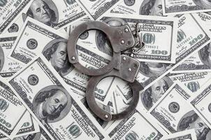 Police handcuffs lie on a lot of dollar bills. The concept of illegal possession of money, illegal transactions with US dollars. Economic Crime photo