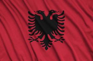 Albania flag is depicted on a sports cloth fabric with many folds. Sport team banner photo