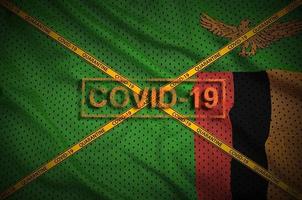 Zambia flag and Covid-19 stamp with orange quarantine border tape cross. Coronavirus or 2019-nCov virus concept photo