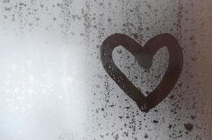 The heart is painted on the misted glass in winter photo