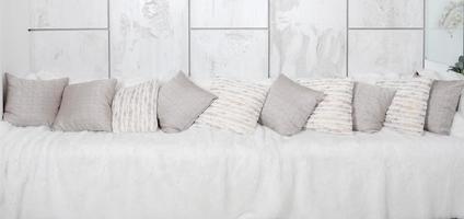 Many pillows lie on the couch, which is covered with a large plush veil against the background of a marble wall photo