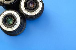 Several photographic lenses lie on a bright blue background. Space for text photo