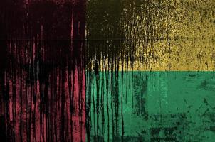 Guinea Bissau flag depicted in paint colors on old and dirty oil barrel wall closeup. Textured banner on rough background photo