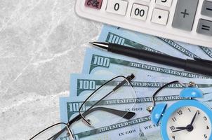 100 US dollars bills and calculator with glasses and pen. Business loan or tax payment season concept. Time to pay taxes photo