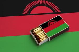 Malawi flag is shown in an open matchbox, which is filled with matches and lies on a large flag photo