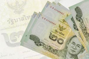 20 Thai Baht bills lies in stack on background of big semi-transparent banknote. Abstract presentation of national currency photo