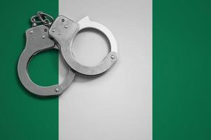 Nigeria flag and police handcuffs. The concept of crime and offenses in the country photo