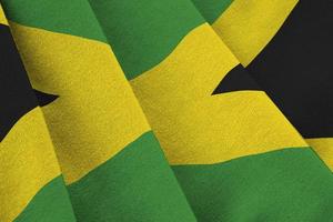 Jamaica flag with big folds waving close up under the studio light indoors. The official symbols and colors in banner photo