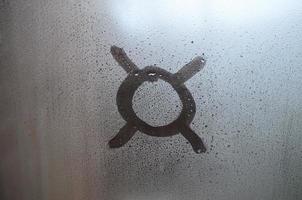 Currency sign is written with a finger on the surface of the misted glass photo