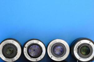 Several photographic lenses lie on a bright blue background. Space for text photo