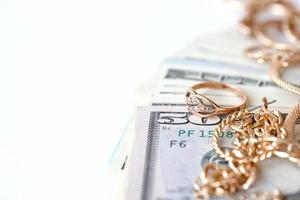 Many expensive golden jewerly rings, earrings and necklaces with big amount of US dollar bills on white background. Pawnshop or jewerly shop photo