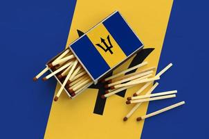 Barbados flag is shown on an open matchbox, from which several matches fall and lies on a large flag photo