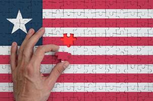 Liberia flag is depicted on a puzzle, which the man's hand completes to fold photo