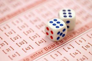 los cubos de dados se encuentran en hojas de juego rosas con números para marcar para jugar a la lotería. concepto de juego de lotería o adicción al juego. de cerca foto