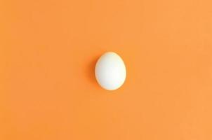 One white easter egg on a bright orange background photo