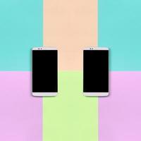 Two modern smartphones with black screens on background of fashion pastel pink, blue, coral and lime colors photo