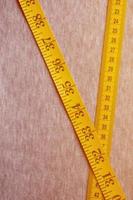 Yellow measuring tape lies on a gray knitted fabric photo