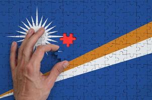 Marshall Islands flag is depicted on a puzzle, which the man's hand completes to fold photo
